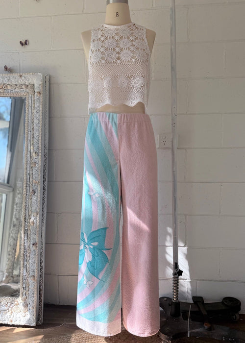 Mannequin wearing a white lace top and pink pants with butterfly design against a white wall.