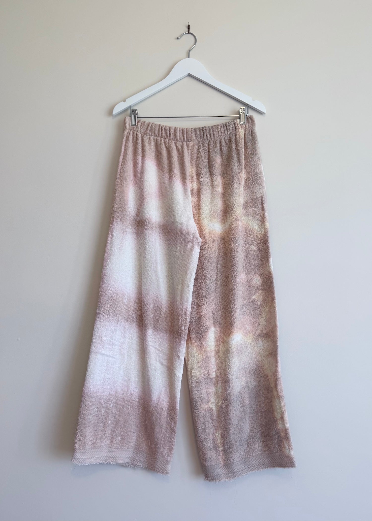 Tie-dye pants on a hanger against a plain background