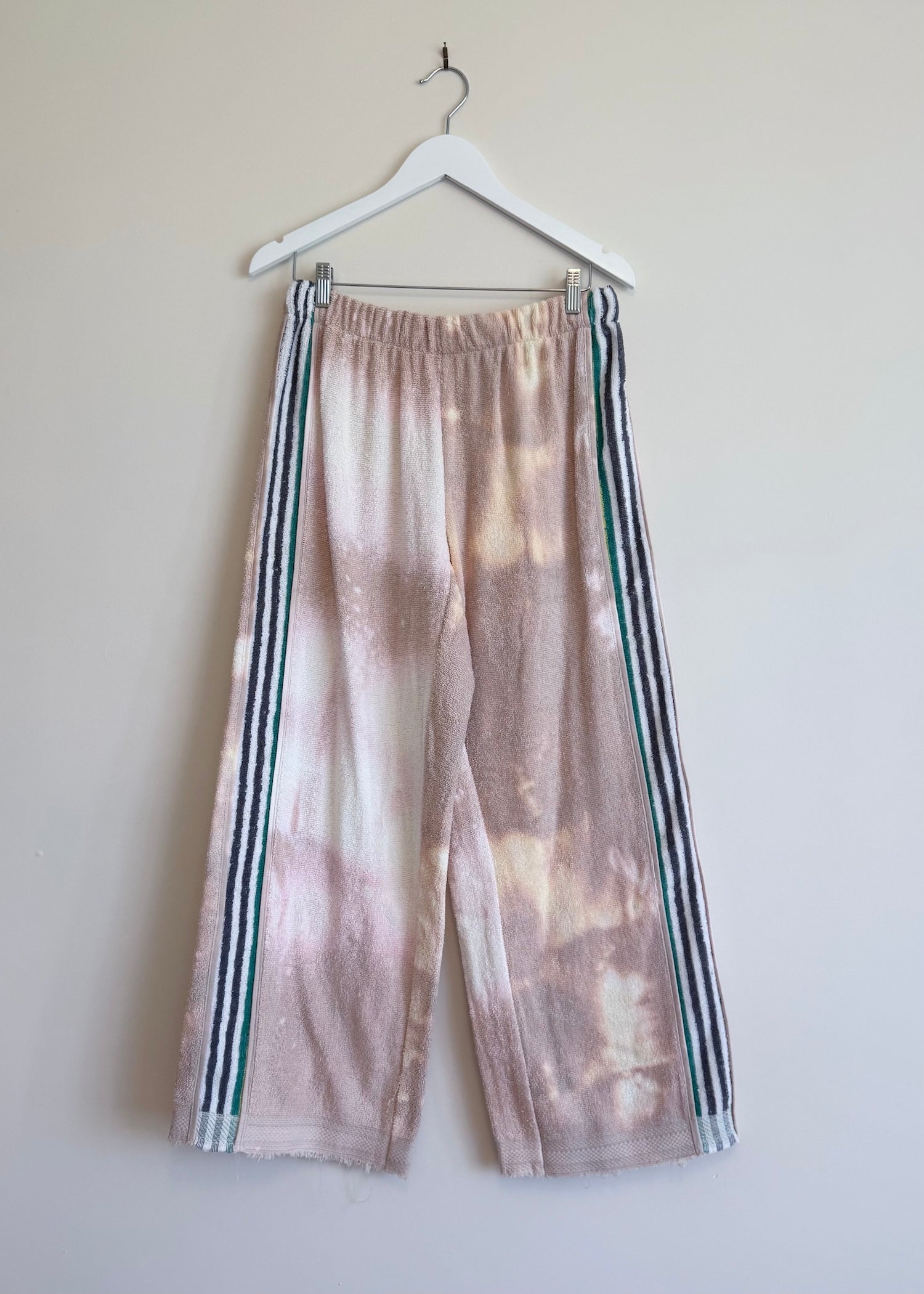 Tie-dye pants with stripes on a hanger against a plain background