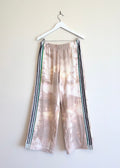 Tie-dye pants with stripes on a hanger against a white background