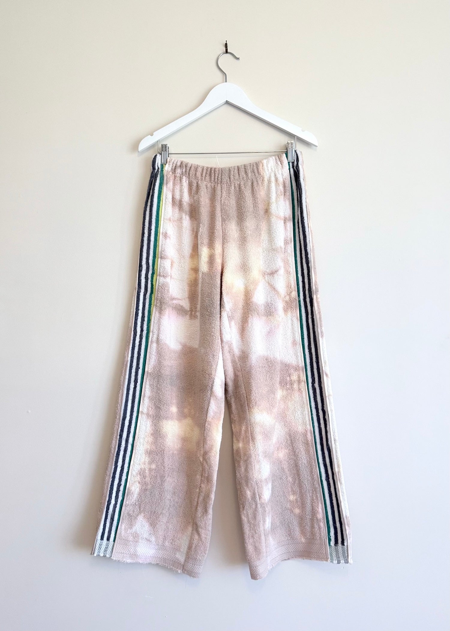 Tie-dye pants with stripes on a hanger against a white background