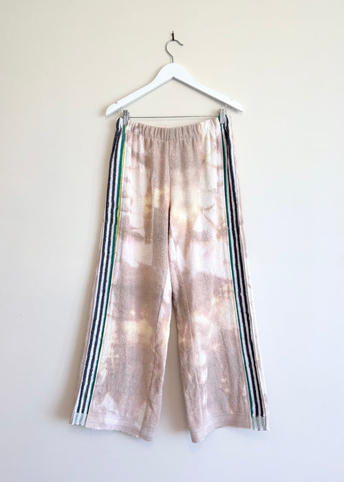 Tie-dye pants with stripes on a hanger against a white background