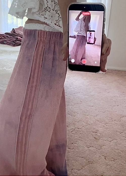 Person wearing a sheer pink skirt with a phone showing a video call in the background.