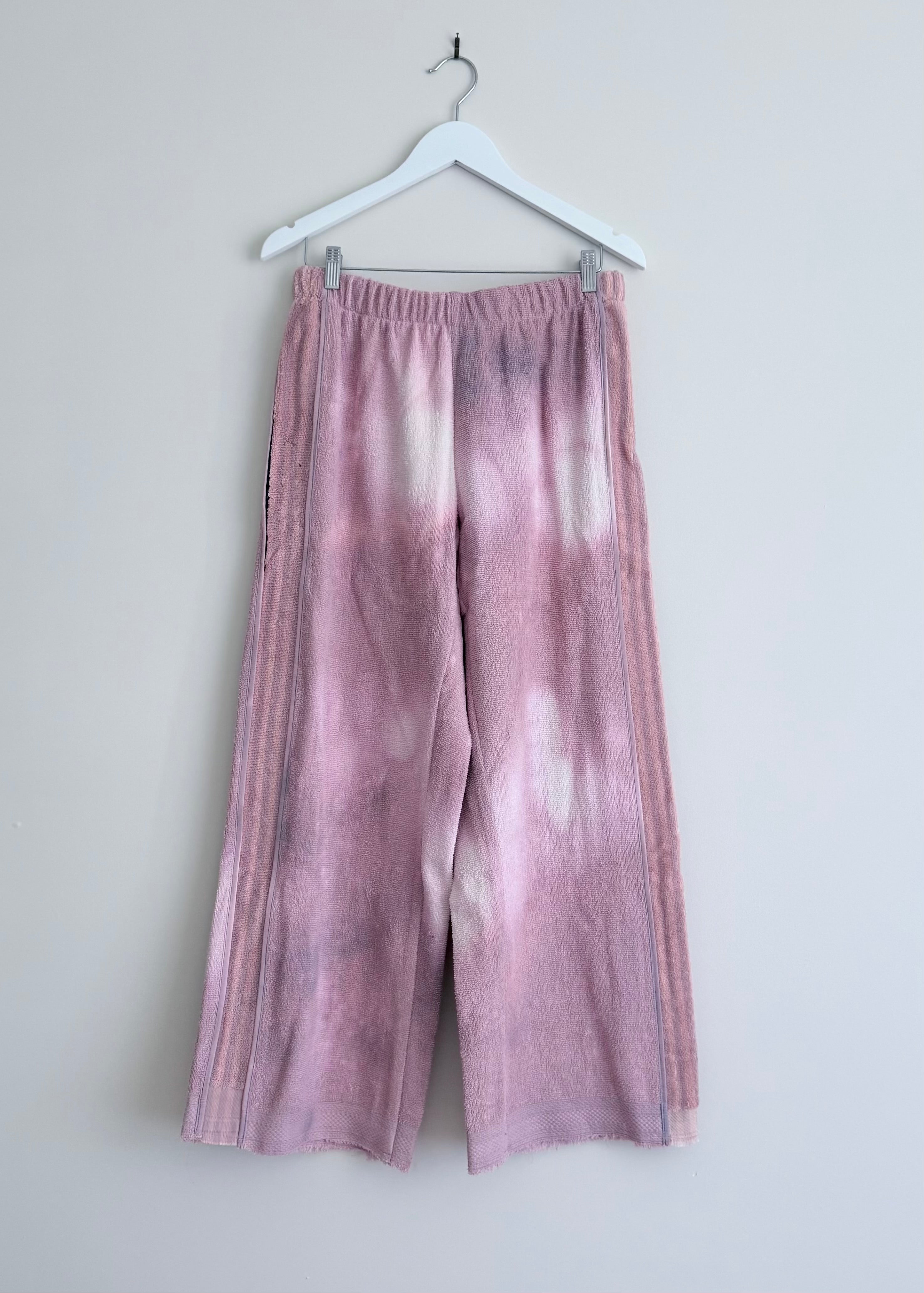 Tie-dye pants hanging on a white hanger against a light gray background