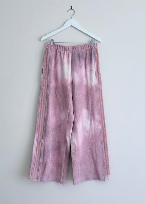 Tie-dye pants hanging on a white hanger against a light gray background
