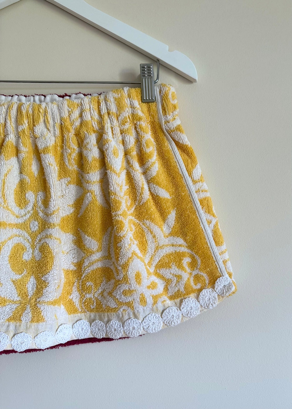 Yellow and white patterned towel hanging on a rack against a plain wall.